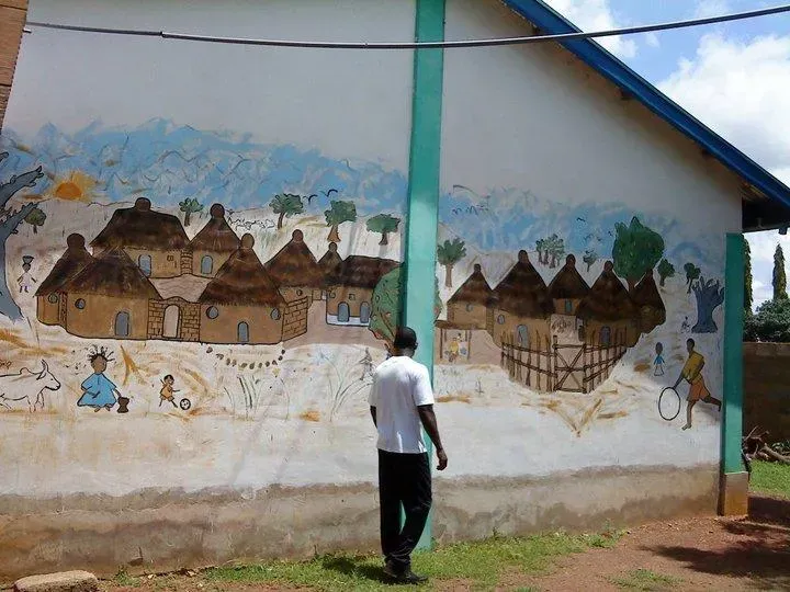 Clement Matorwmasen in front of the Dream Village mural he painted at New Life College, Tamale, in 2007